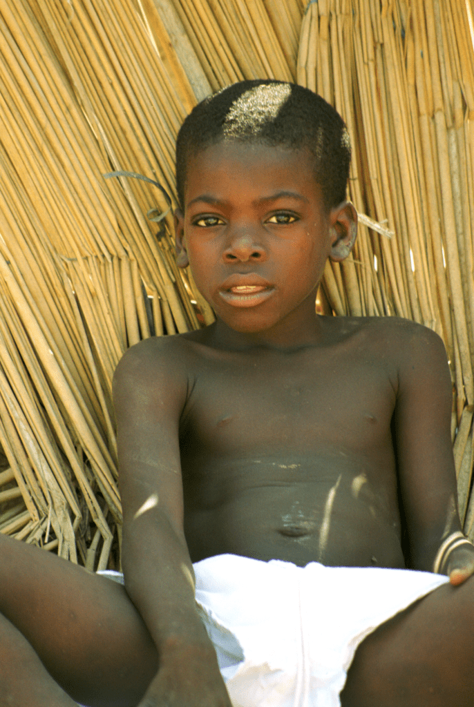 Luanda boy in white shorts against straw