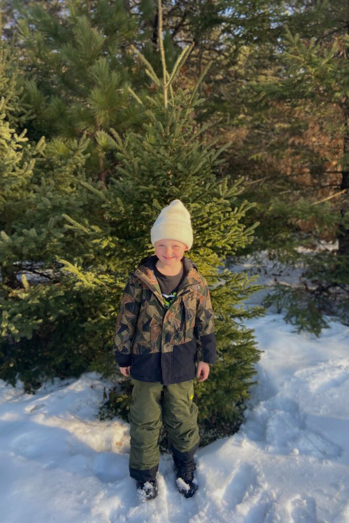 Young boy standing infront of a tree